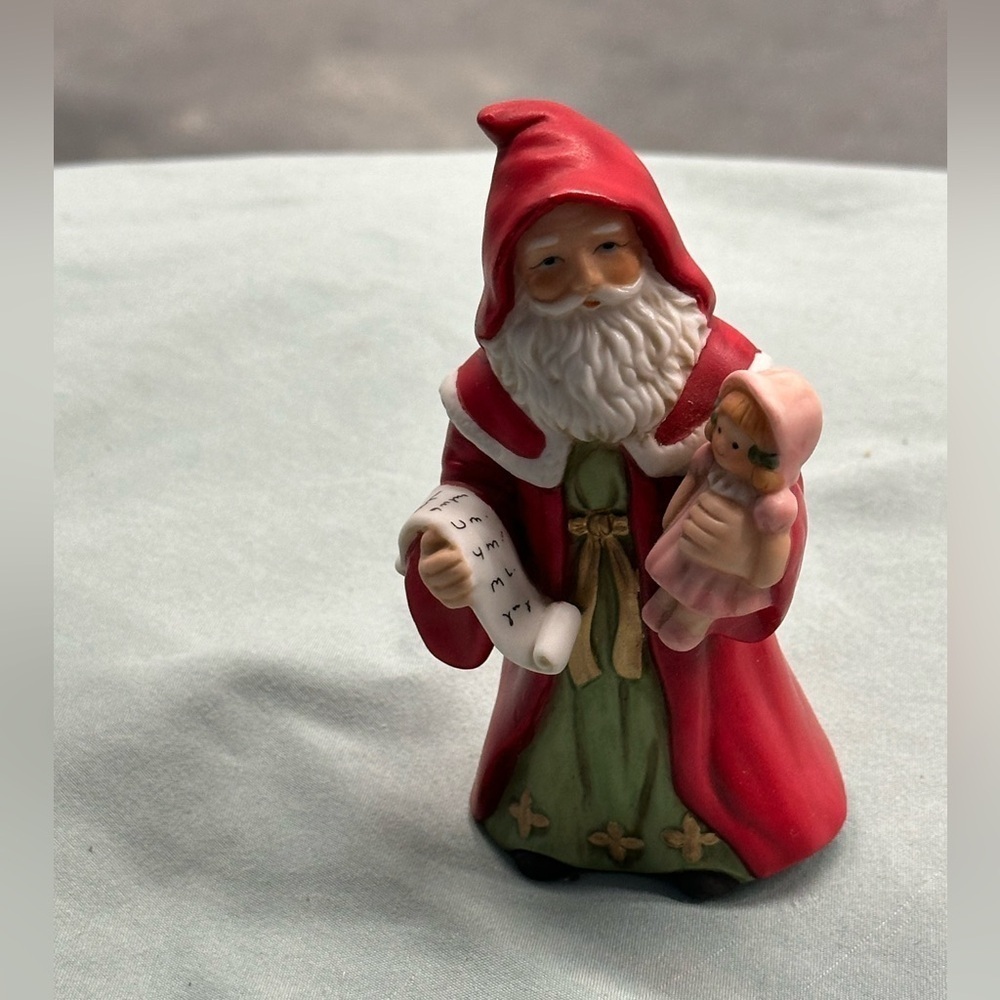 Small porcelain Santa figure.Santa carries a doll and a copy of his list.